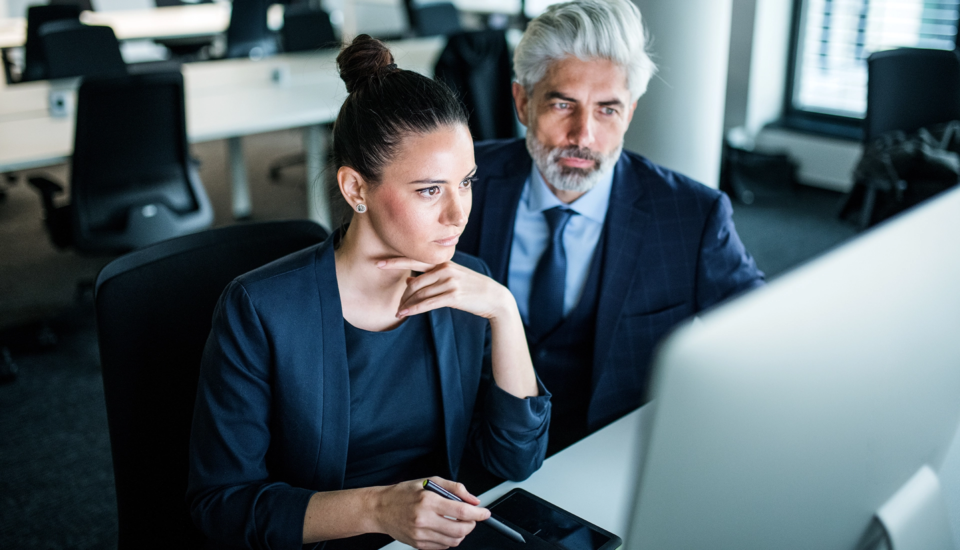 Equipo analizando información en la pantalla de un ordenador en su lugar de trabajo.