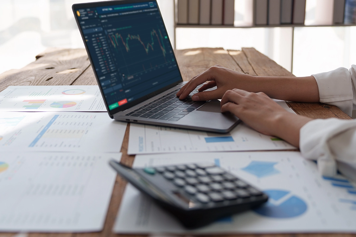 Imagen recortada de una mesa de trabajo donde se están revisando estadísticas y gráficos de datos financieros.